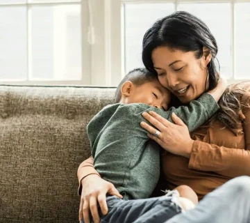 پسر بچه آسیایی در بغل مادر روی کاناپه